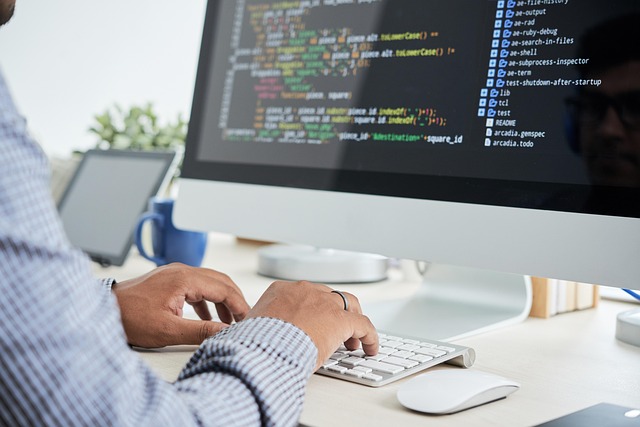 A person typing code on a desktop computer screen