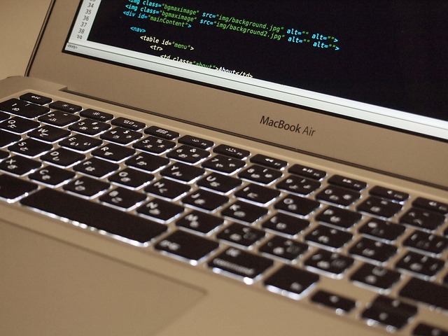 A MacBook laptop keyboard and screen displaying HTML code