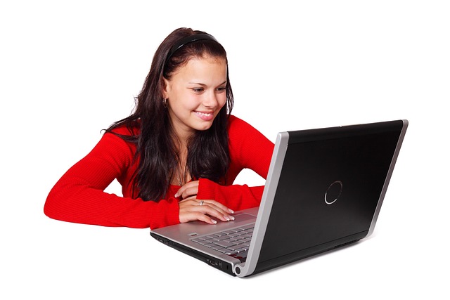 A young woman smiling while using a laptop computer